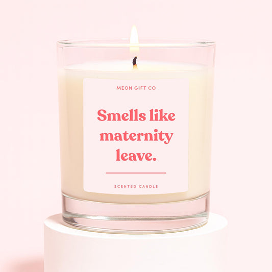 Scented candle in clear glass jar with pink label and lit wick