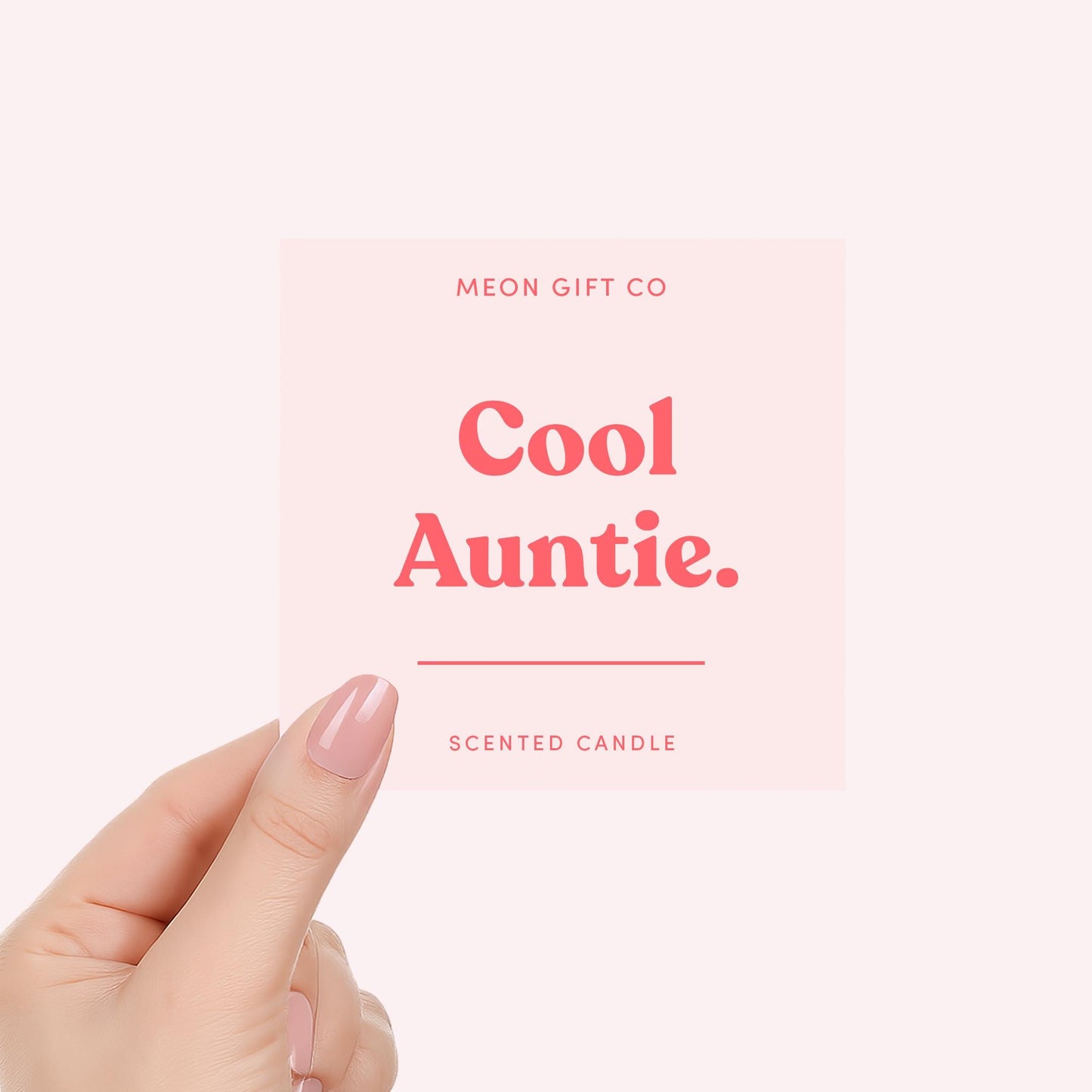 Hand holding “Cool Auntie.” scented candle label with MEON GIFT CO in red