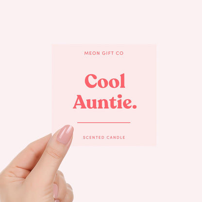 Hand holding “Cool Auntie.” scented candle label with MEON GIFT CO in red