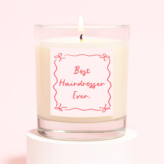 Glass jar candle with cream wax, lit wick, red 'Best Hairdresser Ever' label